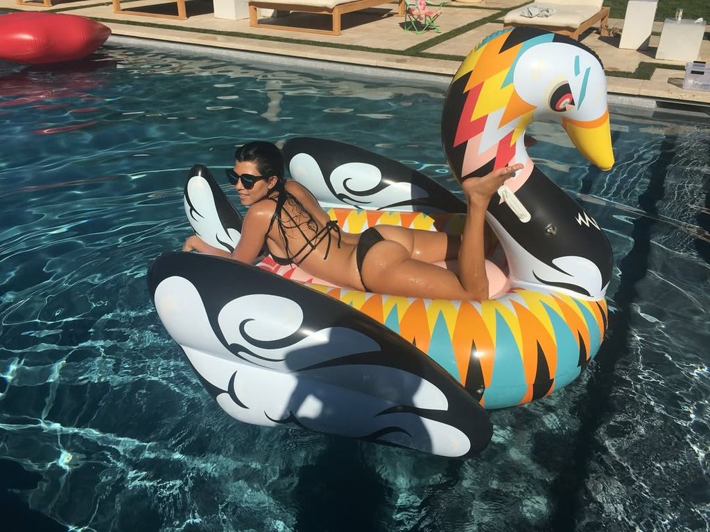 Kourtney Kardashian posing in a black bikini while in the swimming pool - in a throwback from her 2016 nostalgic Instagram post 