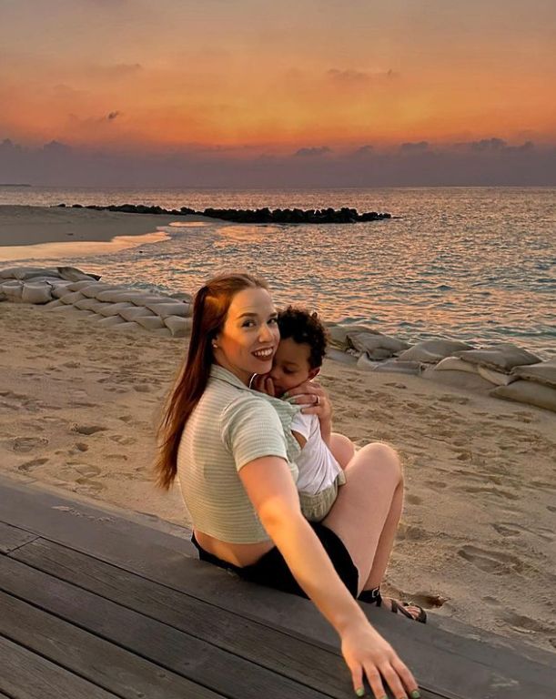 Linda Harrison with a young boy on her lap sitting on the beach