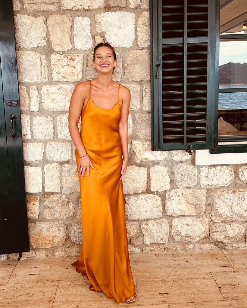 woman standing in front of brick wall in orange dress