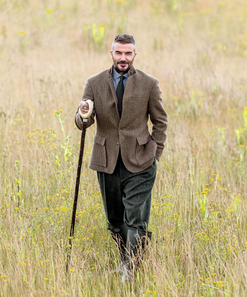David Beckham walking in a field with a walking stick