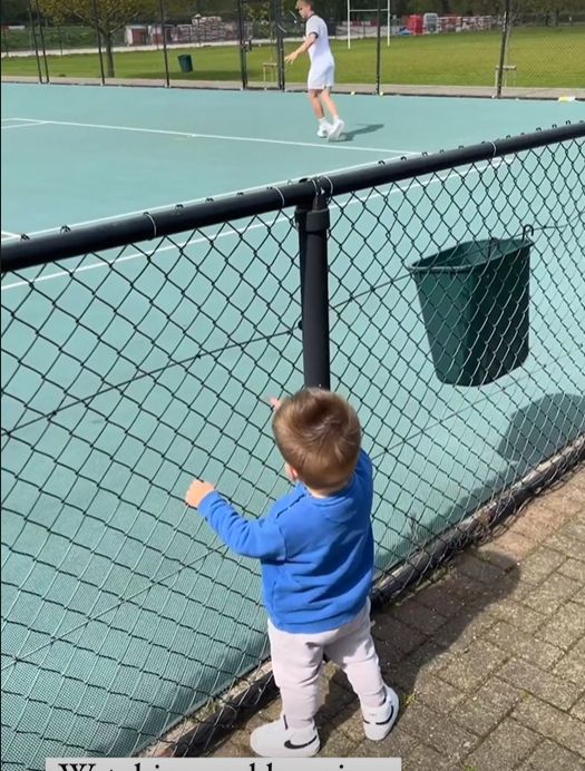 Toddler watching young boy play tennis