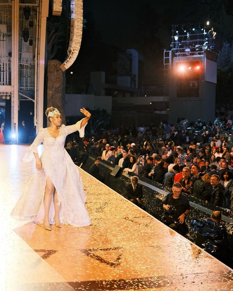 Jennifer Hudson acenando no palco com um vestido brilhante