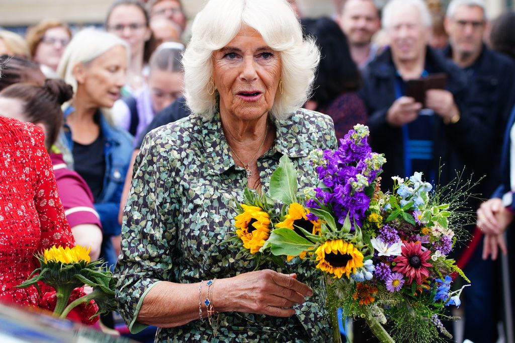 woman in green dress holding bouquet of flowers