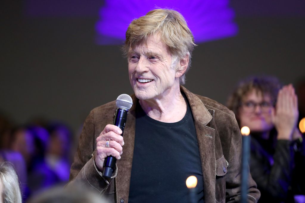 Robert Redford holding a mic and speaking to a crowd while smiling at Sundance Film Festival in 2020