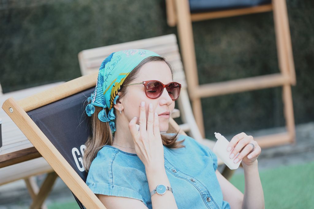 Adult Woman Reapplying SPF Suntan Lotion On Her Light Skin Tone