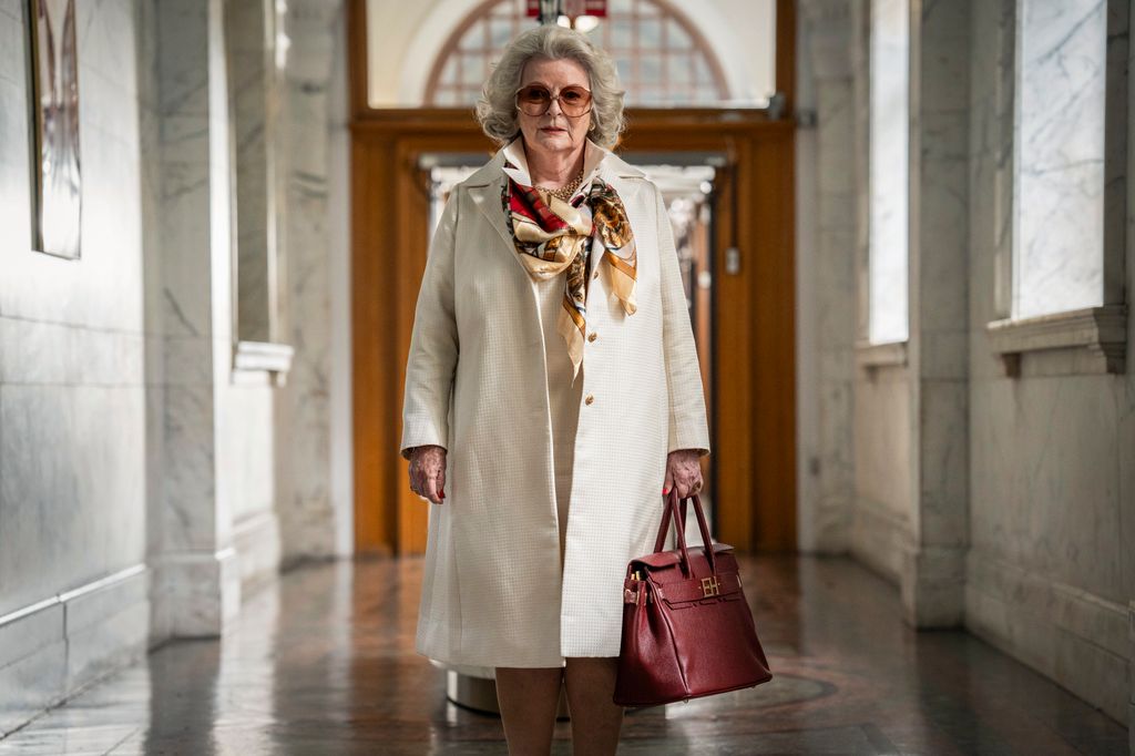 woman walking through hall in cream coat