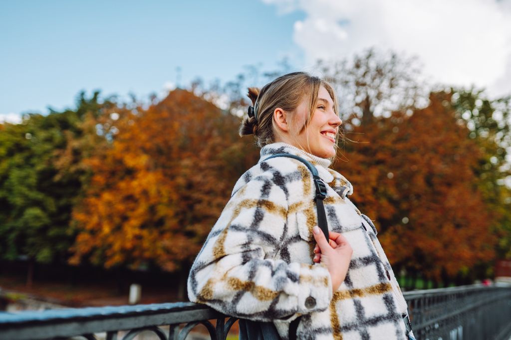 Autumnal city stroll: Smiling blonde woman enjoys a walk on the bridge