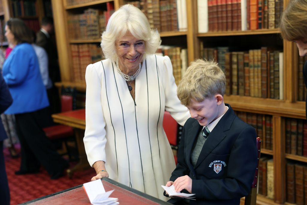 Queen Camilla in a white dress with a young child