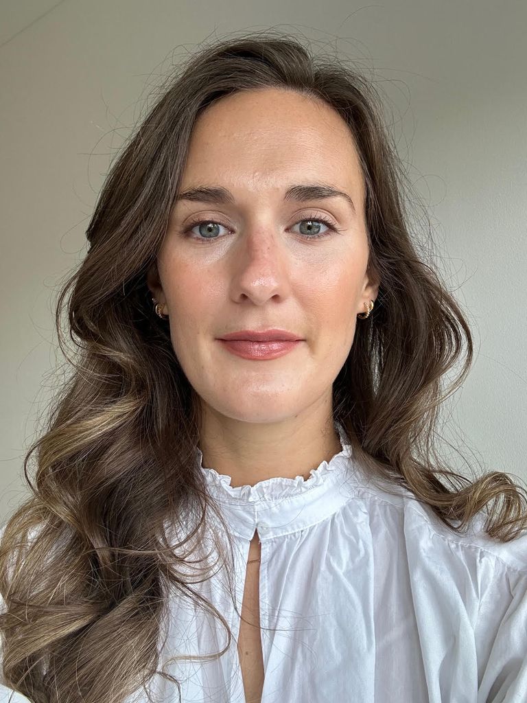 selfie of a woman with tumbling brown hair, wearing a white shirt