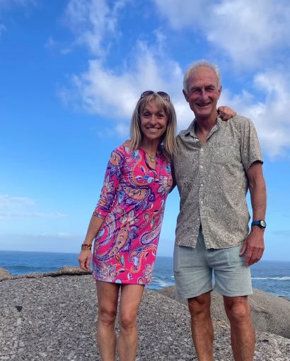 Michaela Strachan in a patterned dress with Nick Chevallier on a stone beach