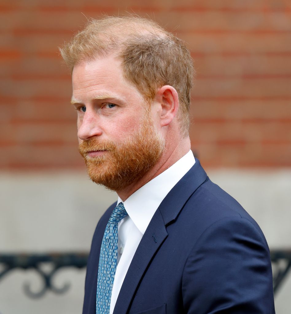 Prince Harry with a stern expression in a blue suit