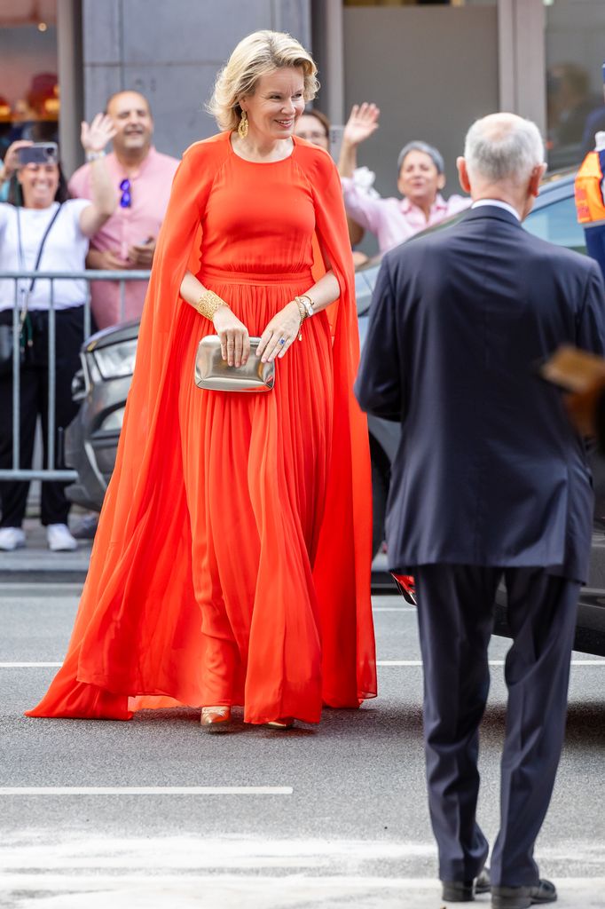 Full-body image of Queen Mathilde in an orange dress