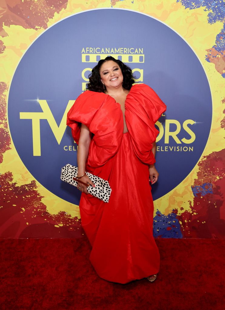 Michelle Buteau posed in red dress with big shoulders