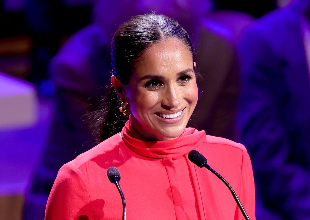 Meghan Markle smiling in a red outfit