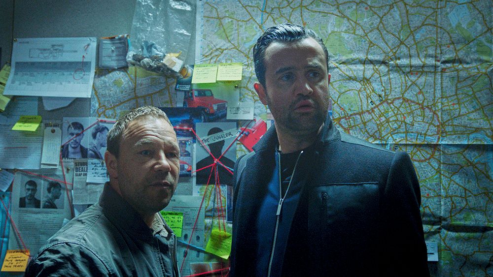 Stephen Graham and Danny Mays standing in front of a suspect board in Code 404