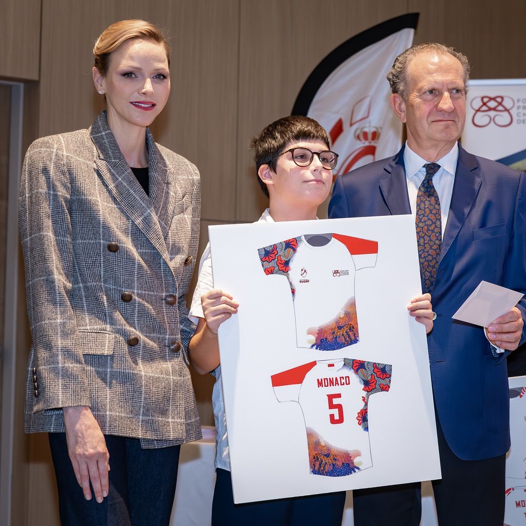 Princess Charlene smiling in grey check blazer