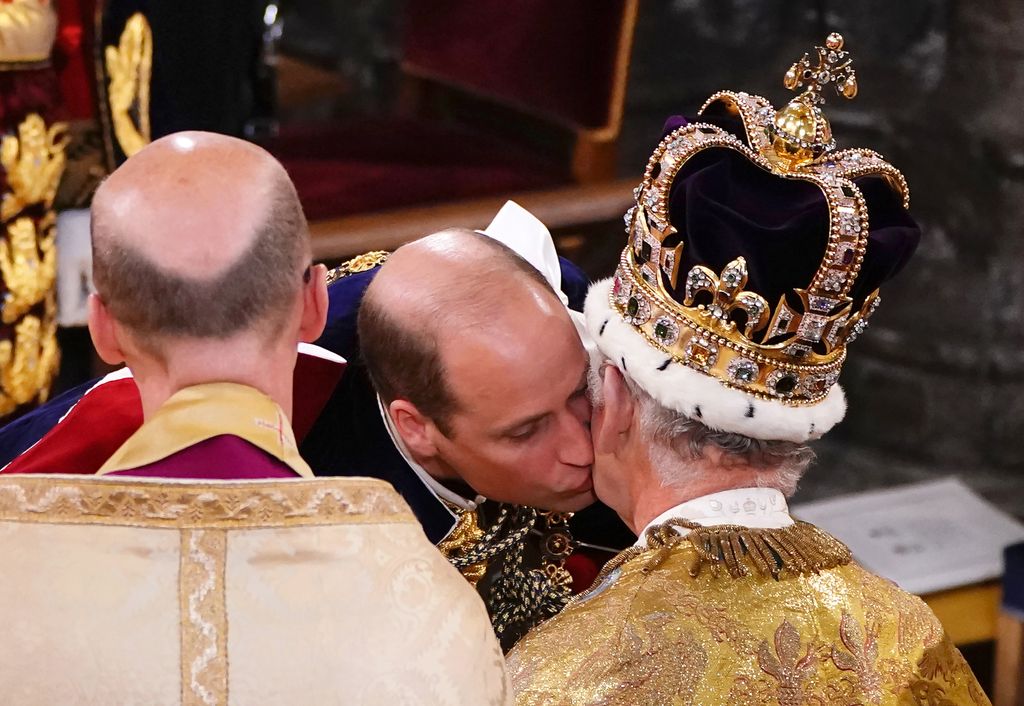 Prince William kisses his father, King Charles III, wearing St Edward's Crown, during the King's Coronation Ceremony inside Westminster Abbey on May 6, 2023