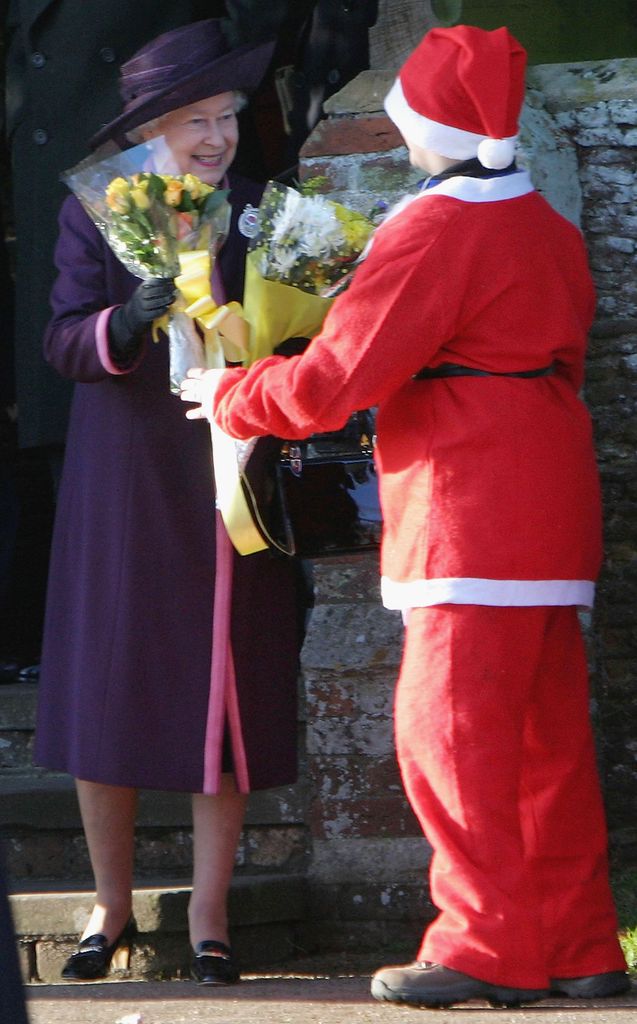 Queen Elizabeth II accepts a bunch of flower from a boy dressed as Father Christmas 