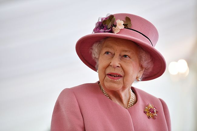 the queen smiles wearing pink coat and hat