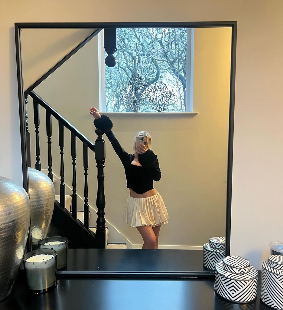 Helen Flanagan wears white mini skirt as she poses on black banister in modern home