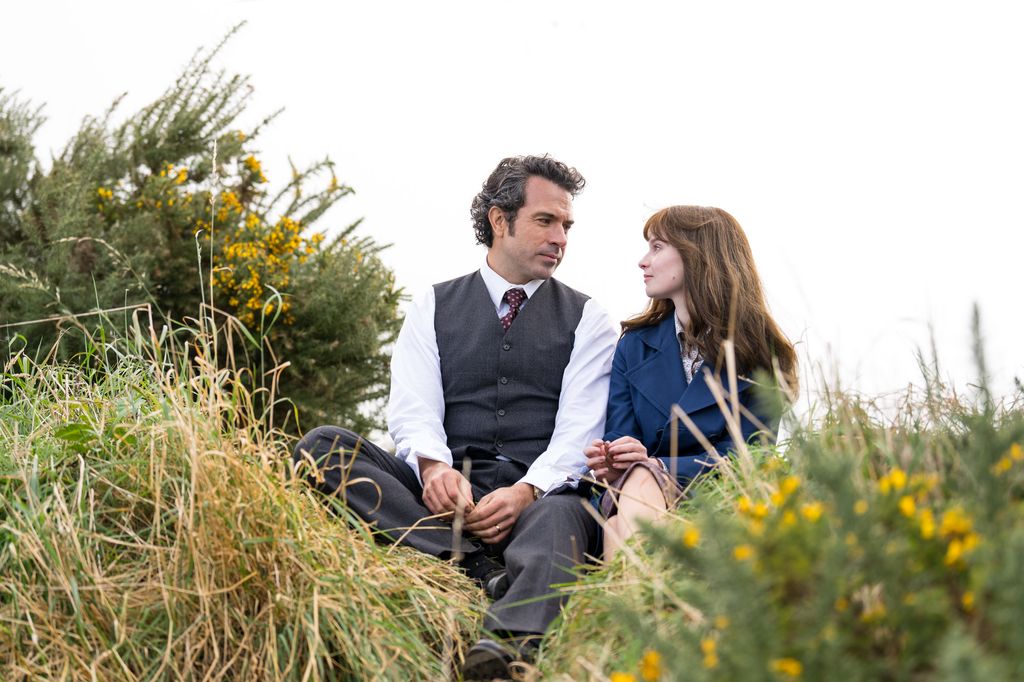 Man and woman sitting on grassy hill