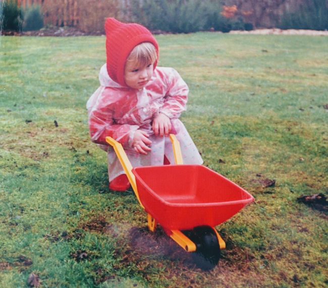 young child with a tiny red wheelbarrow
