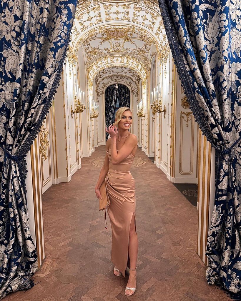 nadiya wearing gold dress in grand hallway 