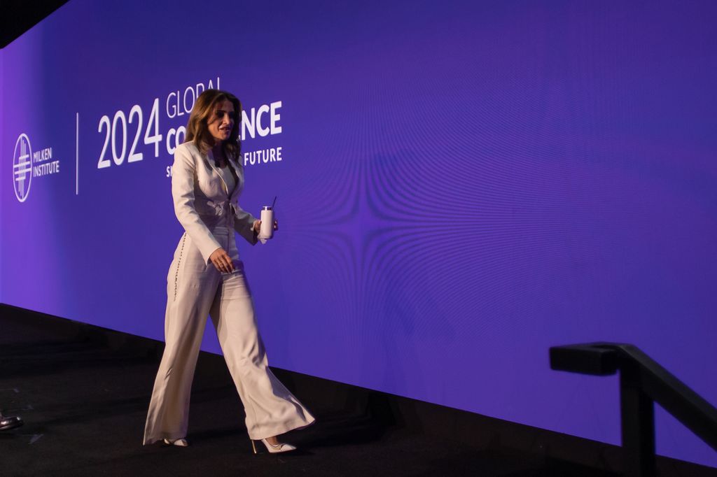 Queen Rania walking off stage in white trousers and blazer