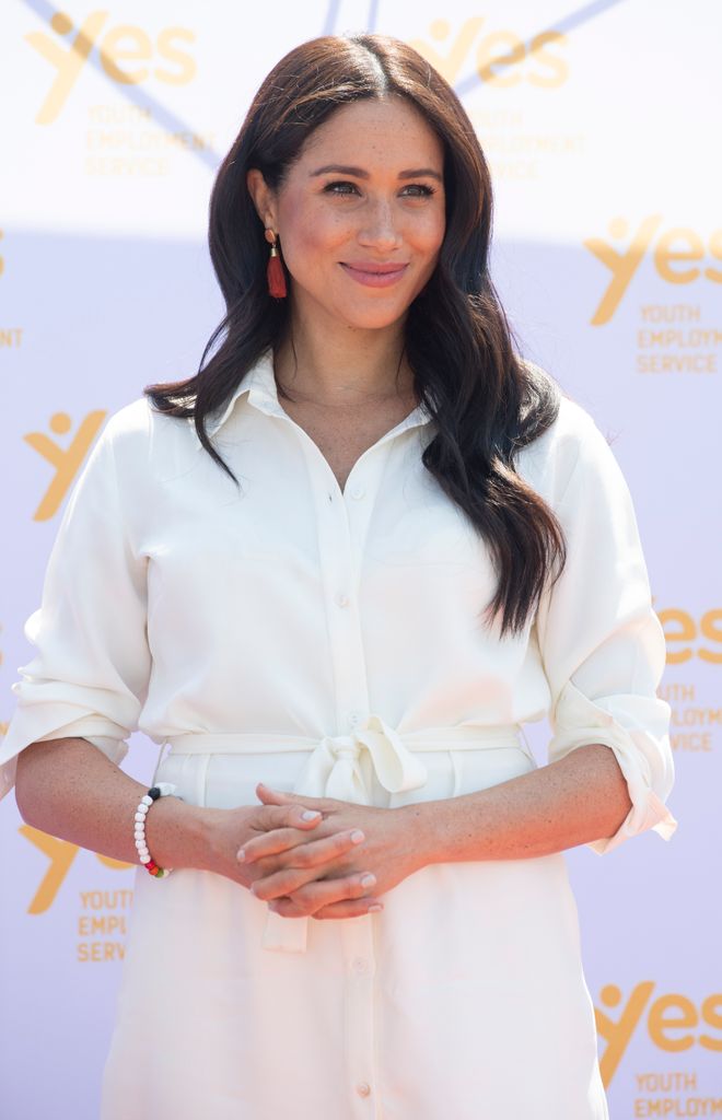 Meghan smiling in white shirt dress