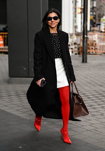 Young beautiful woman in red coat and black tights on the street