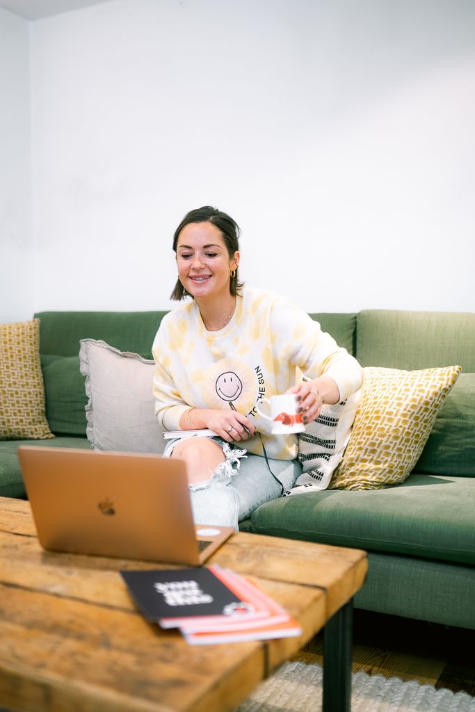 Woman sitting on sofa looking at laptop