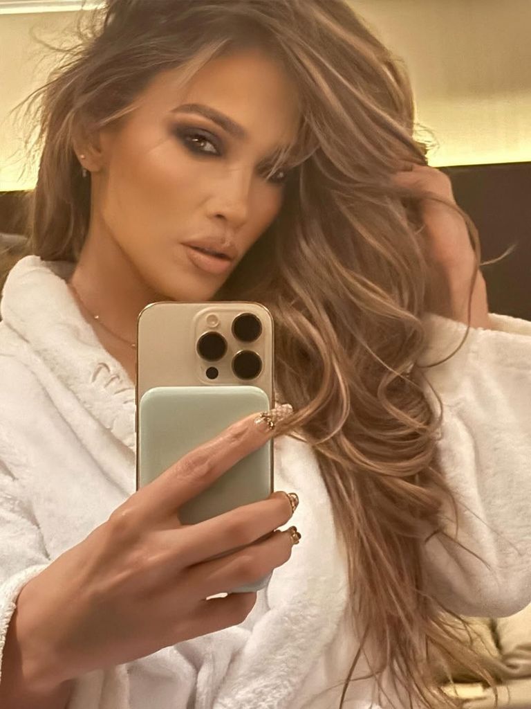 Jennifer lopez in a white robe showing off her long caramel hair 