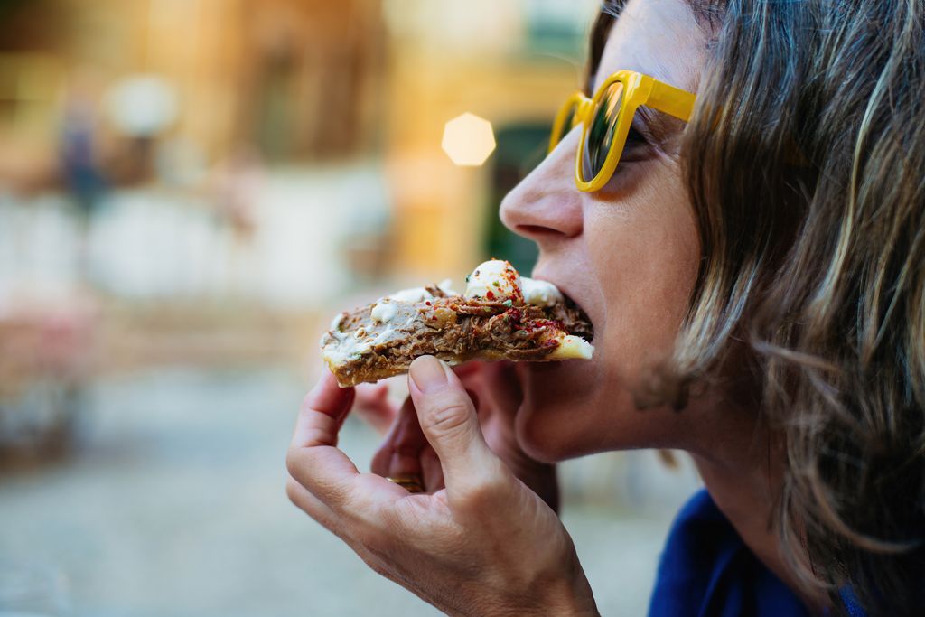 woman eating slice of pizza