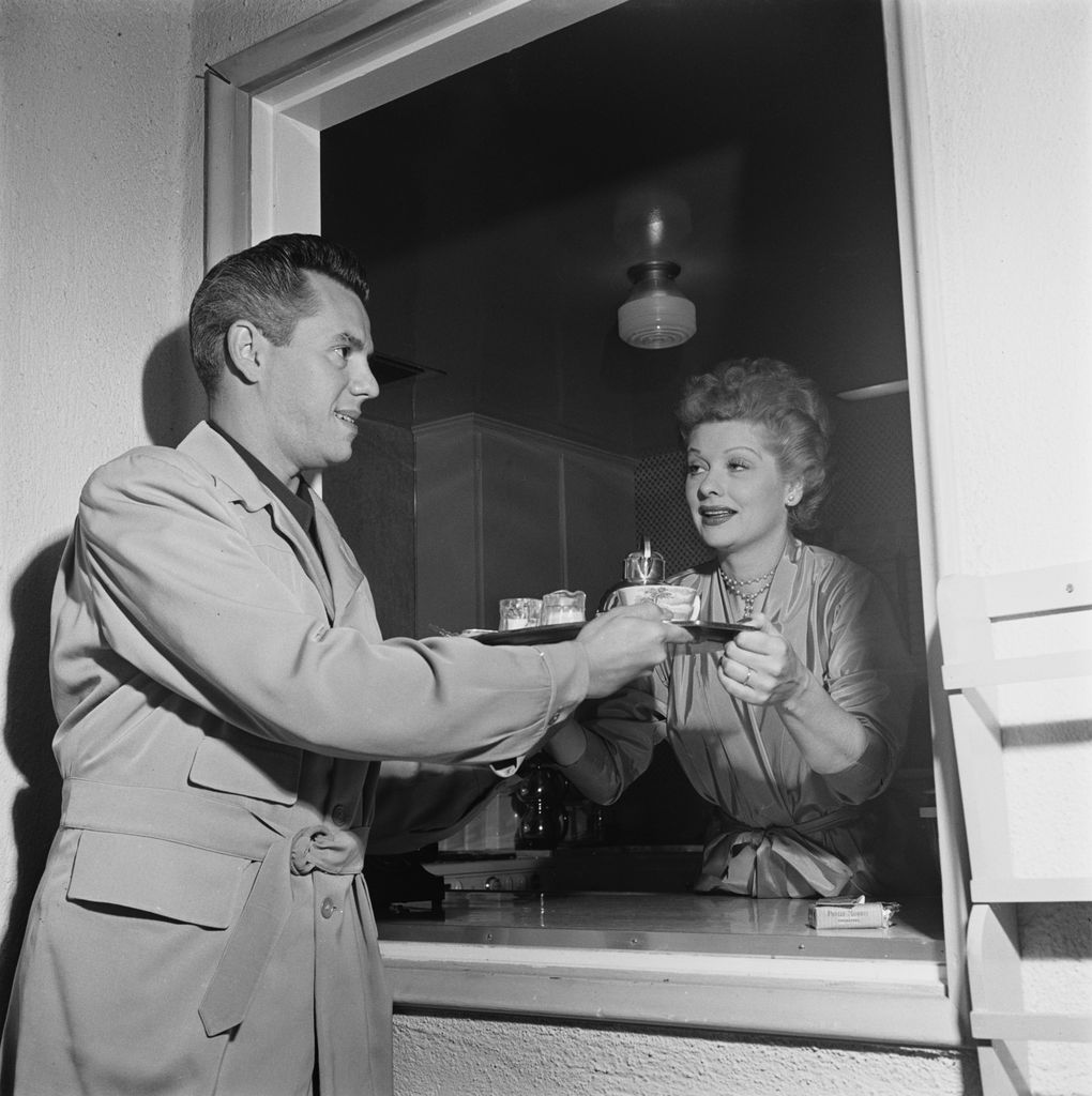 American actress Lucille Ball (1911 - 1989) passing a coffee tray to her husband, actor and musician, Desi Arnaz (1917 - 1986), through a serving hatch at their home, USA, circa 1955.  (Photo by Archive Photos/Getty Images)