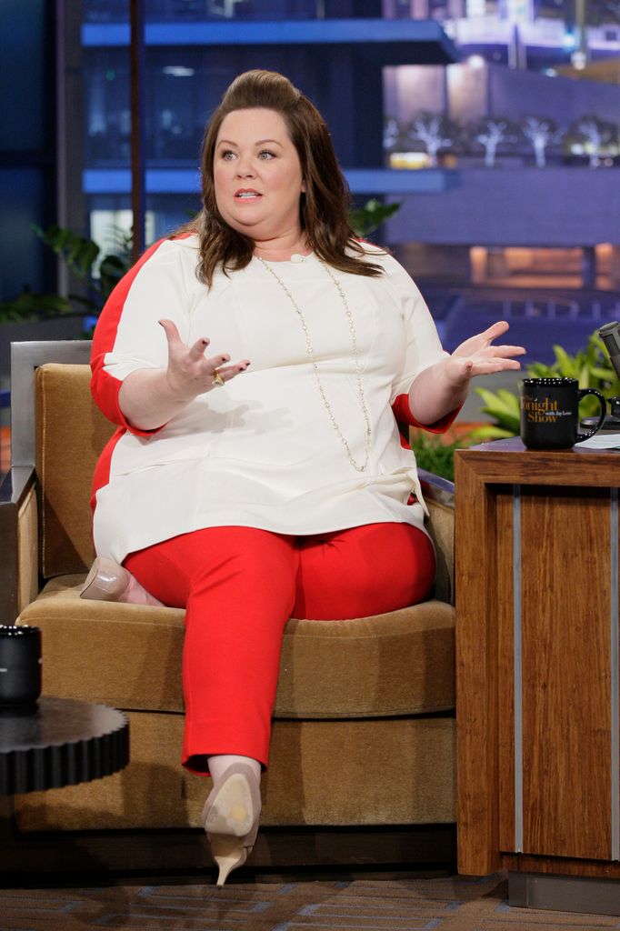 Melissa mccarthy white top red pants sitting