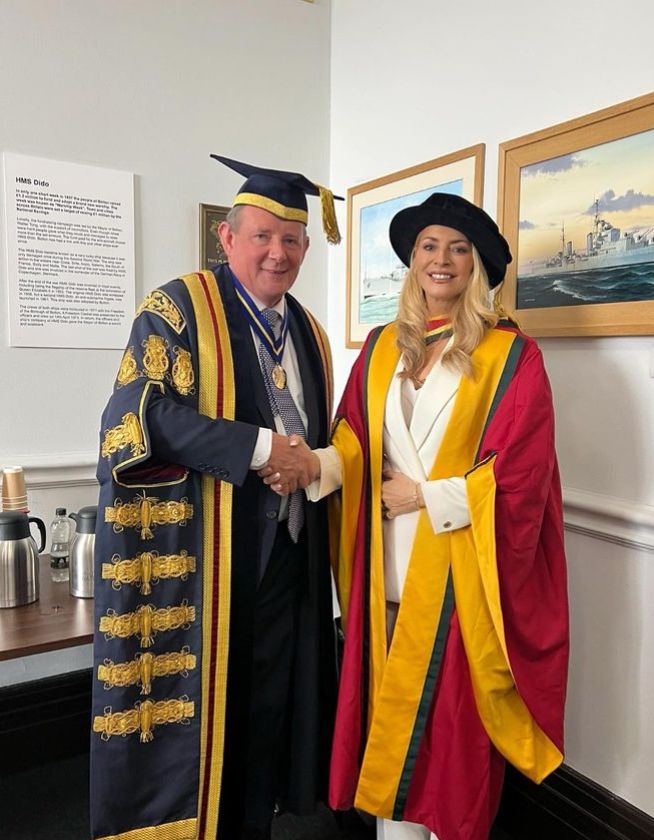 Tess Daly in graduation robes shaking hands with a man