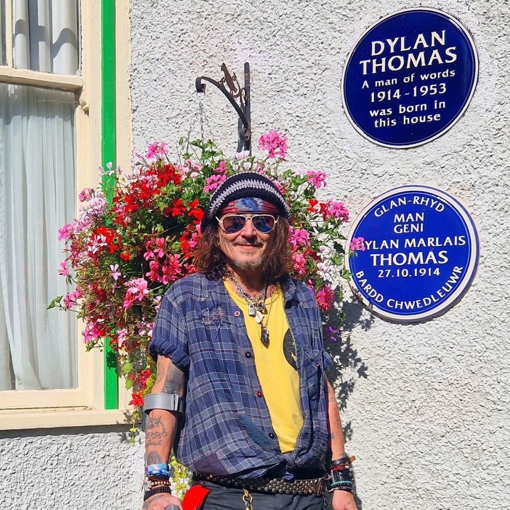 The actor smiling by the blue plaques outside dylan thomas' birthplace