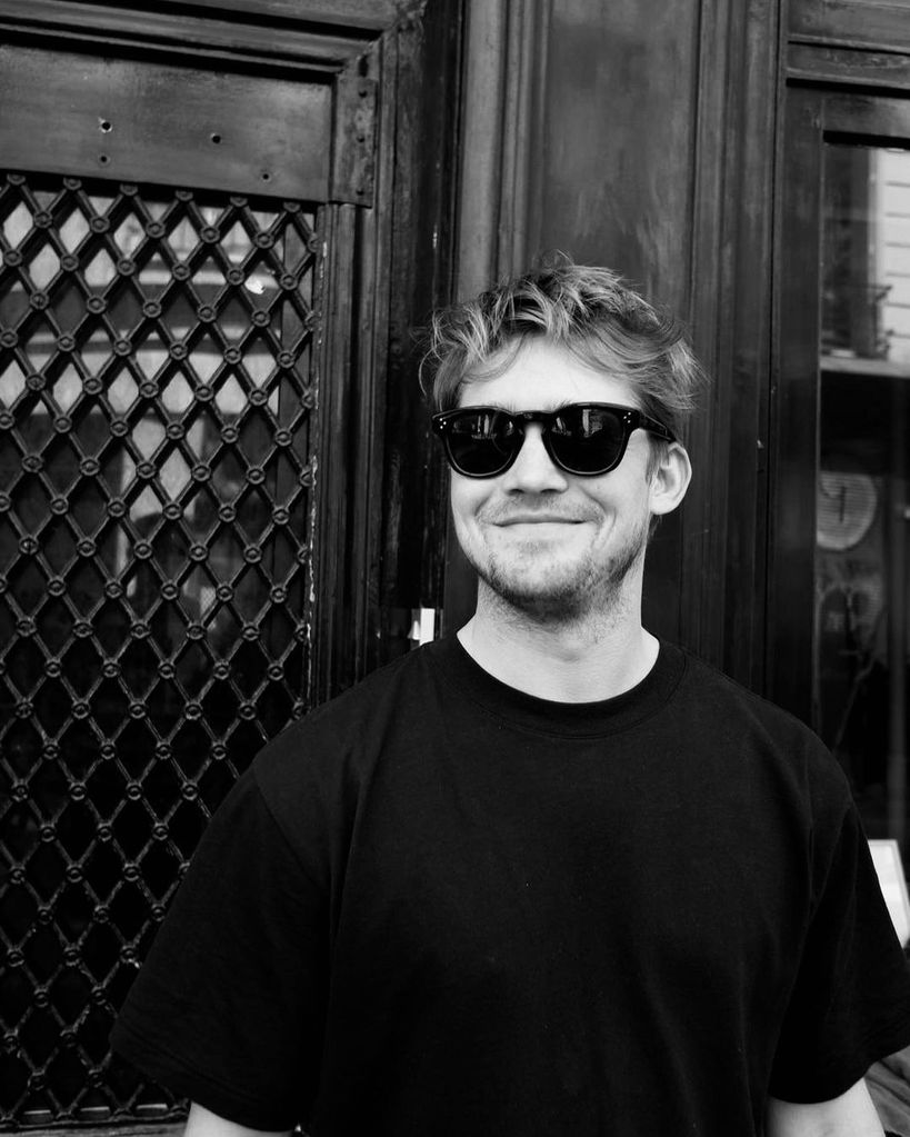 Joe Alwyn smiles in black sunglasses