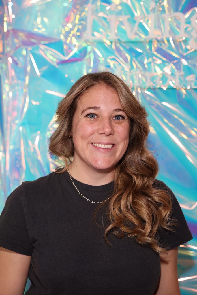 Headshot of Melanie Macleod in a dark t shirt against a shiny holographic background