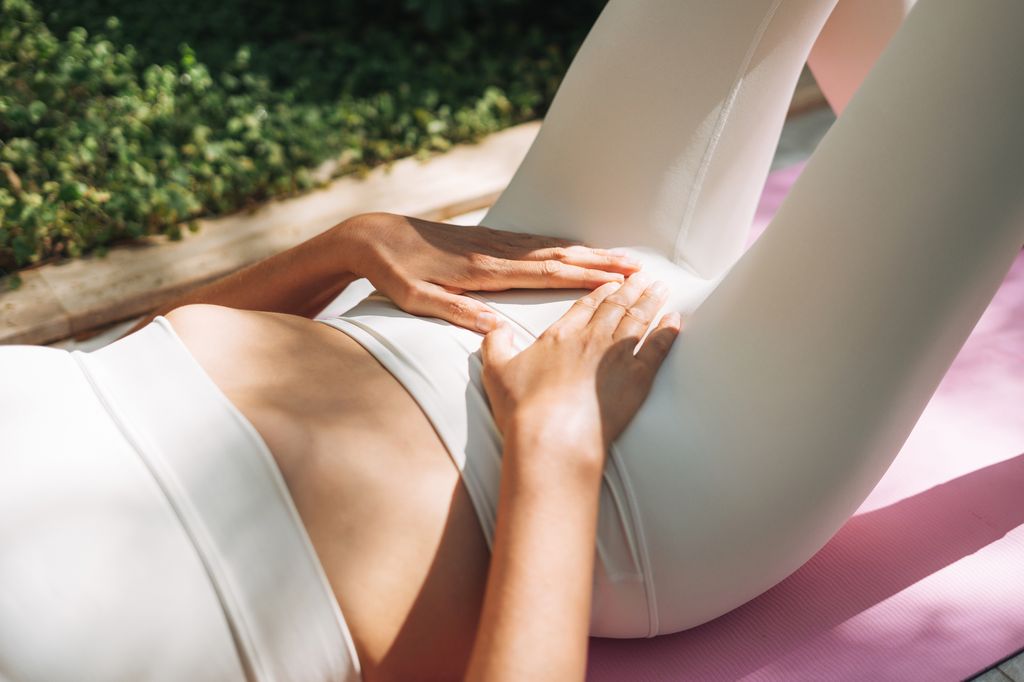 Woman in a white crop top and leggings practices yoga outdoors