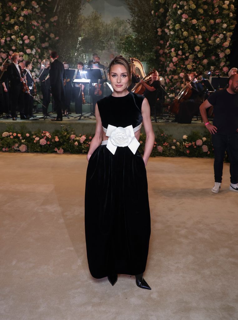 Olivia Palermo posed in room with rose backdrop in black and white dress