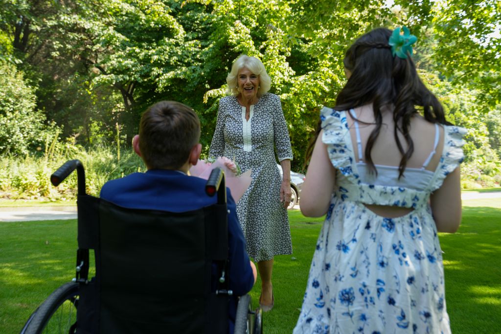 Queen Camilla greeting a young girl and a young boy in a wheelchair