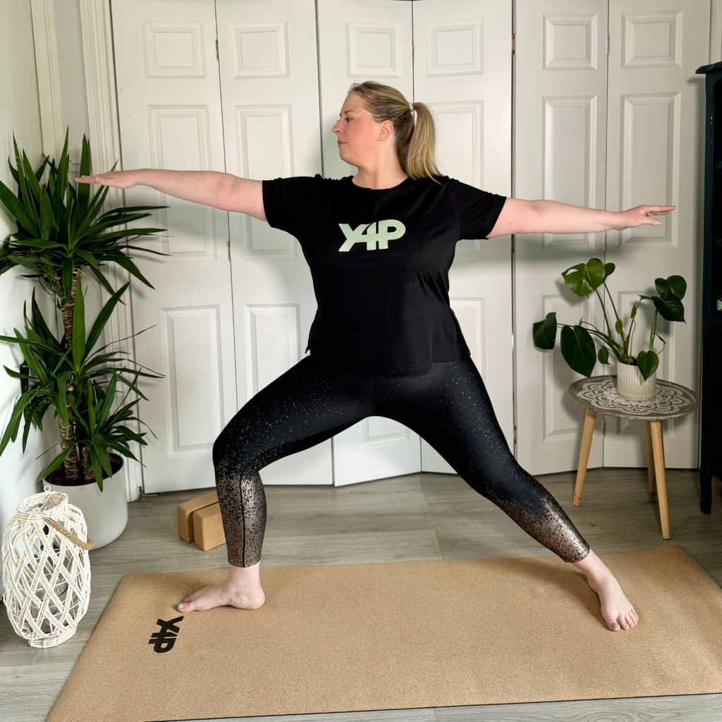 Woman in all black doing yoga at home 