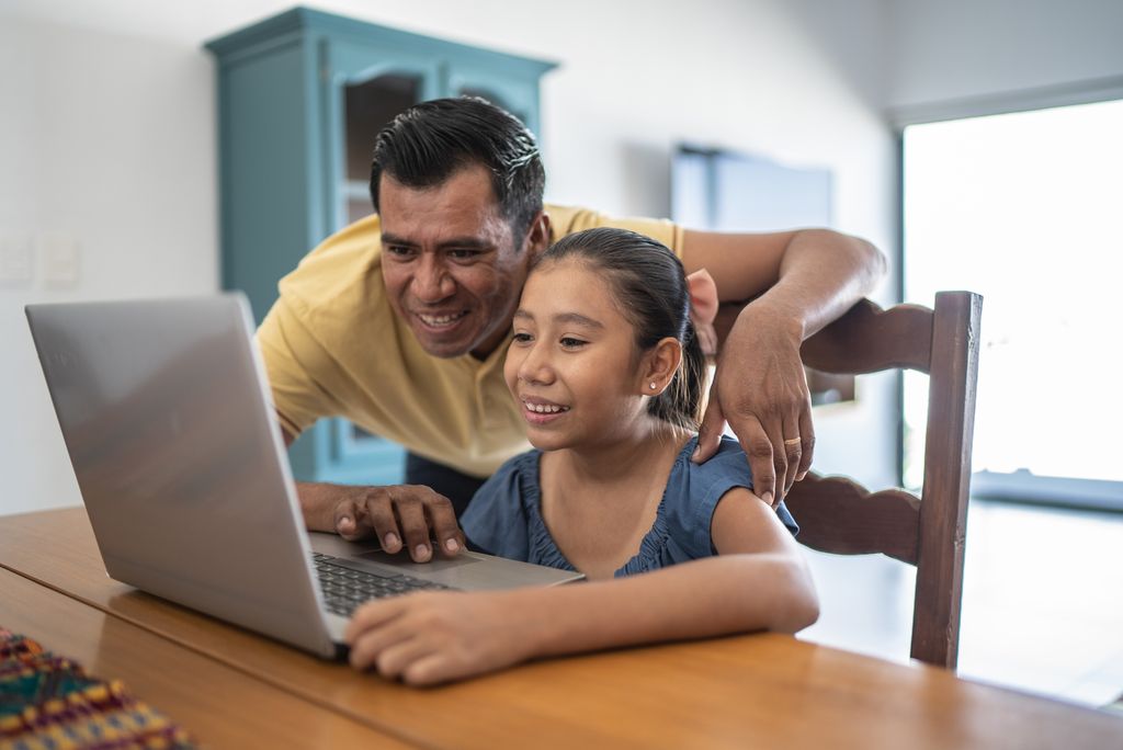 Father helping daughter studying on the laptop at home