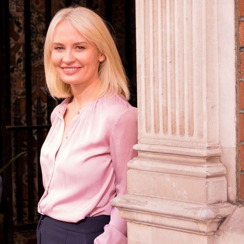 Blonde woman in a pink shirt standing by pillars