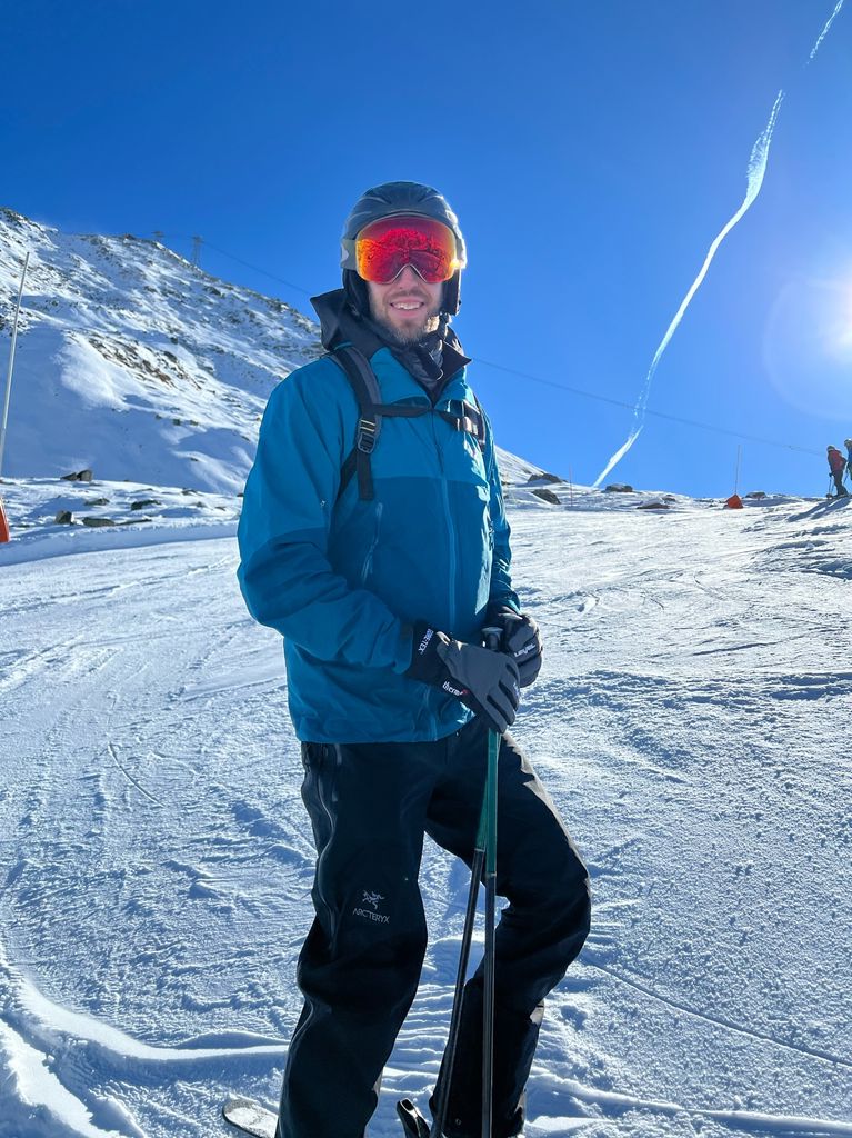 Skier in a blue jacket and orange goggles smiling
