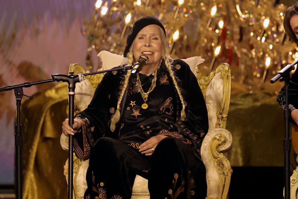 Joni Mitchell speaking on a microphone sitting down