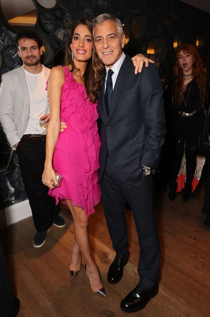 Amal Clooney in pink dress and George Clooney posed at party