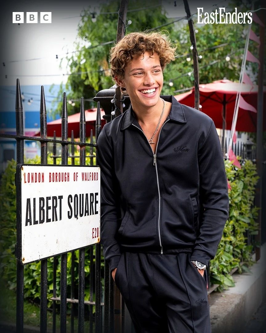 Bobby Brazier in front of the Albert Square sign on the EastEnders set