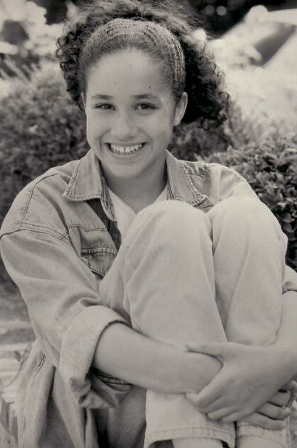 A black-and-white photo of a young Meghan Markle in a denim jacket and jeans